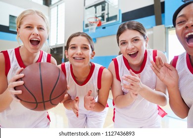 Portrait Of Female High School Basketball Team Celebrating On Court