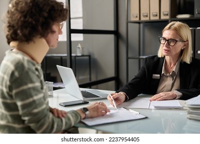 Portrait of female insurance broker consulting injured young woman in office after accident and pointing at legal forms - Shutterstock ID 2237954405