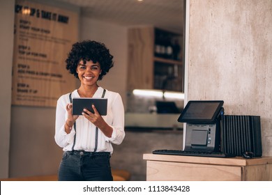 Portrait of female manager in restaurant with digital tablet. Beautiful young african business woman in restaurant using digital tablet.