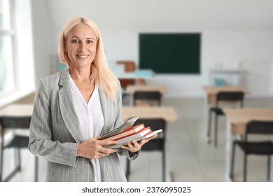 Portrait of female math teacher with calculator and books in classroom - Powered by Shutterstock