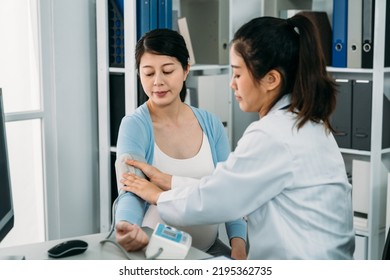 Portrait Female Medical Doctor Is Wrapping The Cuff Around The Expectant Patient’s Arm To Monitor Her Blood Pressure During Pregnancy Checkup In The Hospital.