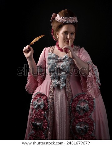 portrait of female model wearing an opulent pink gown,  costume of a historical French baroque nobility, style of Marie Antoinette. Holding feather quill. isolated silhouette on dark background