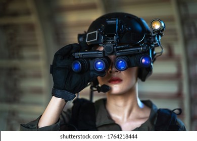 Portrait of female modern army special forces soldier, anti terrorist squad fighter, elite commando warrior using four-eyed night vision goggles in dark background