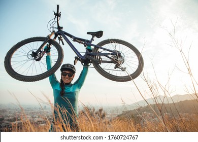 Portrait of female mountain bike on trail. Dressed in blue lifting a double suspension cross country bicycle, xc mtb in the mountain of Collserola in Barcelona