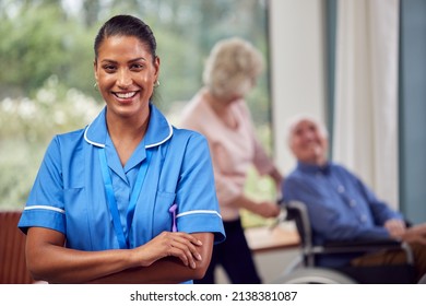 Portrait Of Female Nurse Or Care Worker Making Home Visit To Senior Couple With Man In Wheelchair