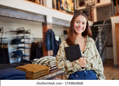 Portrait Of Female Owner Of Fashion Store Using Digital Tablet To Check Stock In Clothing Store