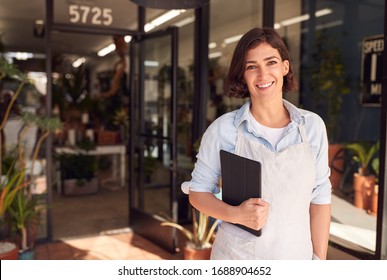 Portrait Of Female Owner Of Florists With Digital Tablet Standing In Doorway Surrounded By Plants - Powered by Shutterstock