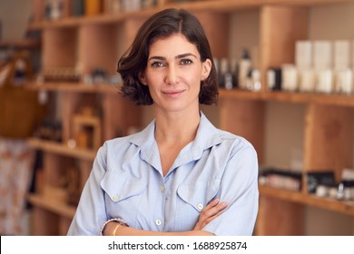 Portrait Of Female Owner Of Gift Store Standing In Front Of Shelves With Cosmetics And Candles