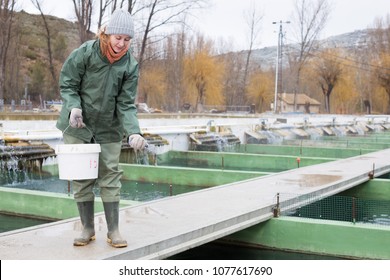 Portrait Of Female Owner On Sturgeon Farm Feeding Fish
