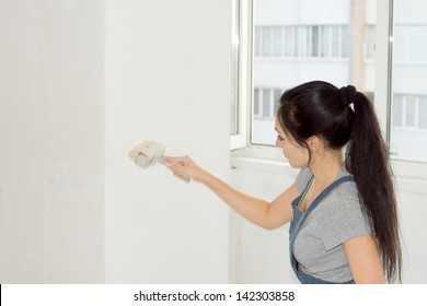 Portrait of female painting a wall with a roller as she decorates her home - Shutterstock ID 142303858