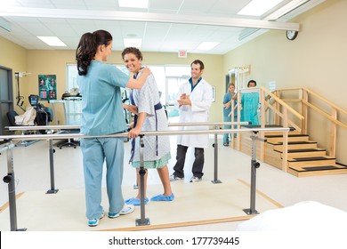Portrait of female patient being assisted by physical therapist while doctor applauding