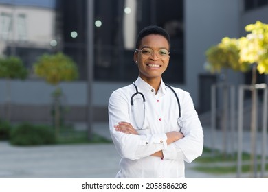 Portrait of female pediatrician doctor happy successful smiling and looking at camera near clinic in medical gown