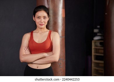 portrait female personal trainer smiling and crossed arms pose in the gym - Powered by Shutterstock