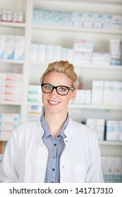 Portrait of a female pharmacist smiling in front of medicines at drugstore
