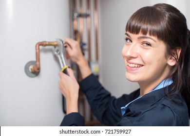 Portrait Of Female Plumber Working On Central Heating Boiler