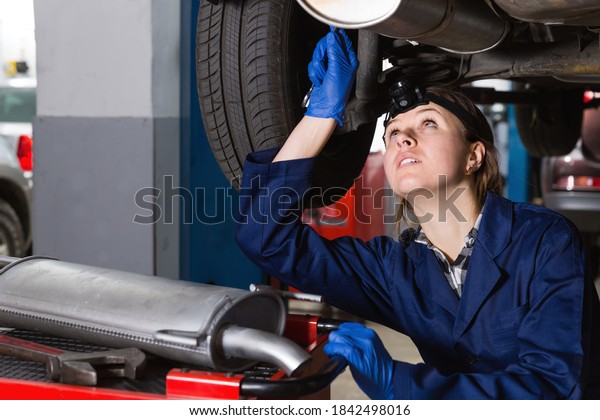 Portrait of female professional master\
repairing car at\
workplace