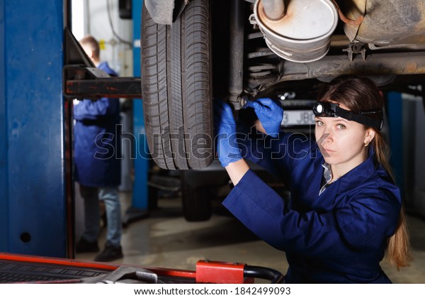 Portrait of female professional master\
repairing car at\
workshop.