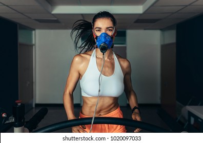 Portrait Of Female Runner Wearing Mask On Treadmill In Sports Science Lab. Sportswoman Running On Treadmill And Monitoring Her Fitness Performance.