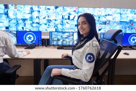 portrait of female security operator while working in a data system control room offices Technical Operator Working at  workstation with multiple displays, security guard working on multiple monitors