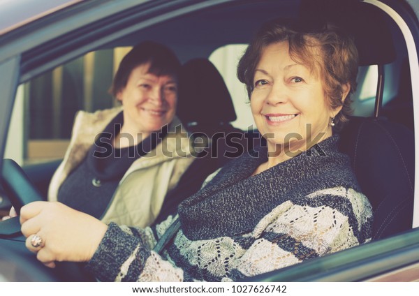 Portrait of\
female senior driver and her friend in\
car
