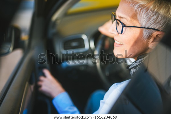 Portrait of female\
senior driver smiling in\
car