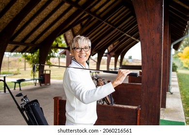 Portrait Of Female Senior Golfer Standing On Golf Course And Smiling.