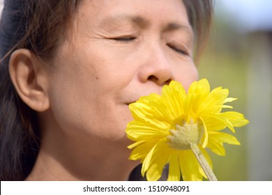 Portrait Of A Female Senior Smelling Flowers