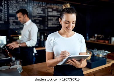 Portrait of female small business owner using digital tablet at restaurant cafe                               