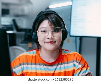 Portrait of Female software developer, Computer programmer looking at camera sits at desk in software and tech company office. Confident Smile Programmer working in Creative office at night.