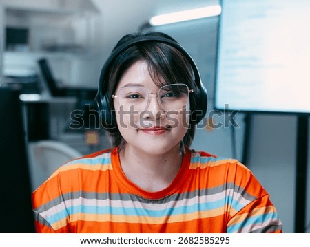 Portrait of Female software developer, Computer programmer looking at camera sits at desk in software and tech company office. Confident Smile Programmer working in Creative office at night.