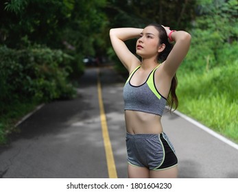 Portrait Of Female In Sportswear Stretching Exercise, Cooling Down After Morning Exercises In Nature 