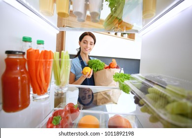 Portrait Of Female Standing Near Open Fridge Full Of Healthy Food, Vegetables And Fruits. Portrait Of Female