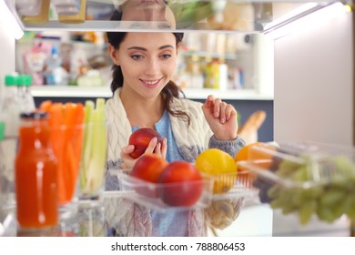 Portrait Of Female Standing Near Open Fridge Full Of Healthy Food, Vegetables And Fruits. Portrait Of Female