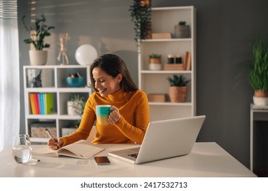 Portrait of a female student working on her project at home while drinking tea. Business woman relaxing while working in an office and drinking coffee during a break. - Powered by Shutterstock