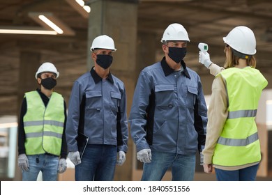 Portrait Of Female Supervisor Measuring Temperature Of Workers With Contactless Thermometer At Construction Site, Corona Virus Safety Measures