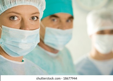 Portrait of female surgeon wearing protective mask on background of her colleagues - Powered by Shutterstock