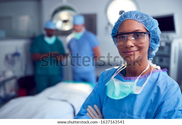 Portrait Of Female Surgeon Wearing\
Scrubs And Protective Glasses In Hospital Operating\
Theater
