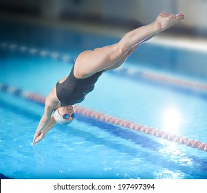 Portrait Of A Female Swimmer, That Jumping And Diving Into Indoor Sport Swimming Pool. Sporty Woman.