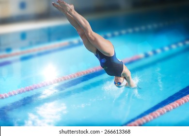 Portrait of a female swimmer, that jumping and diving into indoor sport swimming pool. Sporty woman.