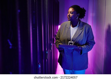 Portrait of female system administrator inspecting data network in server room lit by neon light, copy space - Powered by Shutterstock