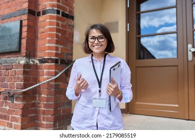 Portrait Of Female Teacher Looking At Camera Outdoor On Steps Of School Building