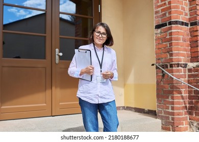 Portrait Of Female Teacher Looking At Camera Outdoor On Steps Of School Building