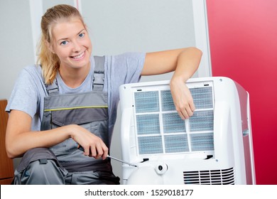 Portrait Of Female Technician Holding Screwdriver By Air Conditioning Unit