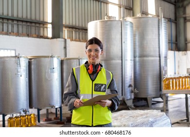 Portrait of female technician writing in clipboard at oil factory - Powered by Shutterstock