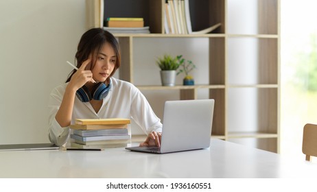 Portrait Of Female University Student Concentrating On Her Online Classroom With Laptop In Living Room