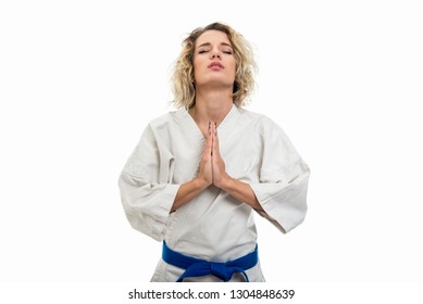 Portrait of female wearing martial arts uniform making prayer gesture isolated on white background - Powered by Shutterstock