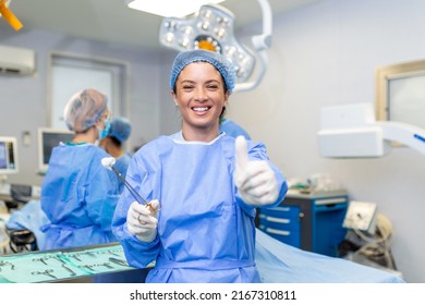 Portrait of female woman nurse surgeon OR staff member dressed in surgical scrubs gown mask and hair net in hospital operating room theater making eye contact smiling thumbs up