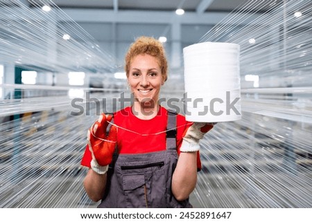 Portrait of female worker holding thread spool in textile factory.