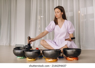 Portrait Of A Female Yoga Teacher Playing A Tibetan Bowl Or Singing A Bell In The Gym During A Yoga Retreat.