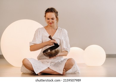 Portrait Of A Female Yoga Teacher Playing A Tibetan Bowl Or Singing A Bell In The Gym During A Yoga Retreat.